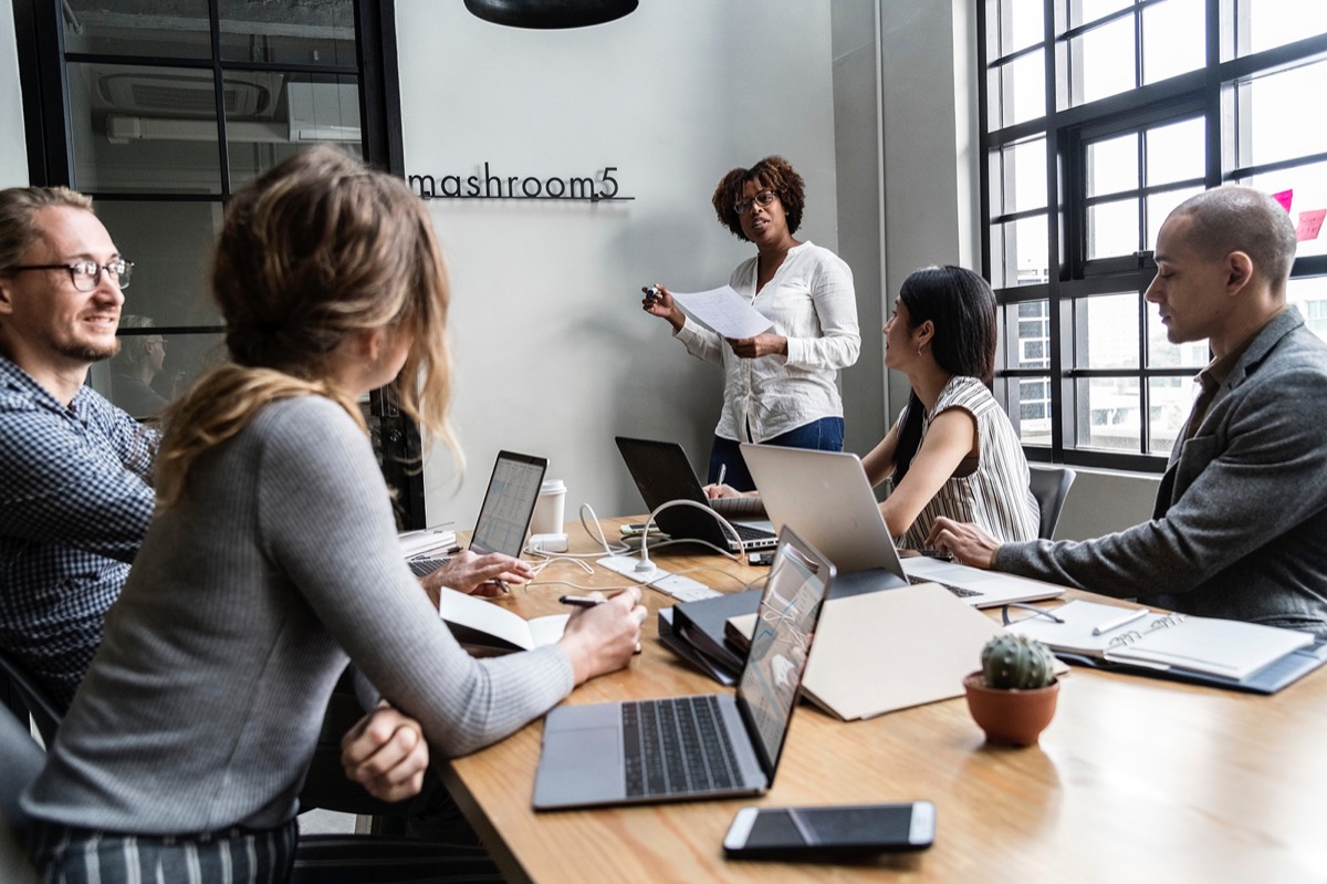 A team meeting around a table with laptops